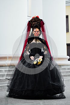 Witch portrait in black vintage dress. Woman widow with red art make-up for halloween.