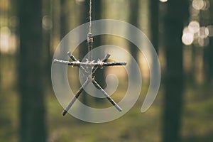 Witchcraft sticks symbol. Magic occult symbol. Totem hanging on tree in dark forest. photo