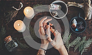 Witches hands on a table ready for spell work. Wiccan witch altar filled with sage evergreen branches herbs crystals