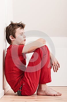 Withdrawn tired boy in red pants and shirt photo