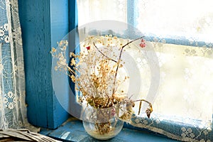 Withered bouquet of wildflowers on an old wooden window of the veranda.