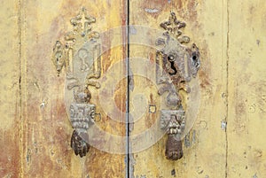 Withered door with iron hands as knockers