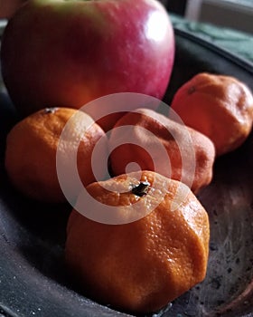 Withered oranges and an apple on a tarnished silver dish