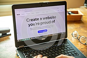 WIX app, provides cloud based web development service. Laptop screen, hand on keyboard
