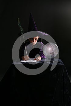 Wizard boy writing with a feather
