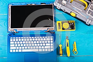 Wizard repairs laptop with tools and hands on the blue wooding table. top view