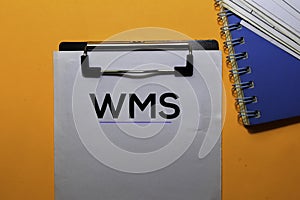 WMS write on paperwork. Isolated on orange table background