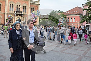 wo Old women passing by in front of a crowd of kids and young children aplaying with balloons in the center of Novi Sad, Voivodina