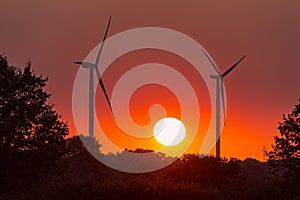 Wo wind turbines under a red sunset in summer