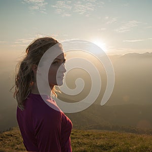 Woamn stands on a peak of mountain at sunset