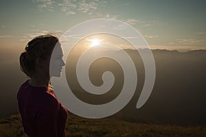 Woamn stands on a peak of mountain at sunset