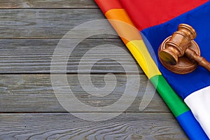 Woden judge mallet symbol of law and justice with lgbt flag in rainbow colours on wooden background