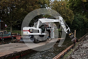 White Cat industrial digger floating on a raft barge on a river canal and excavating the bank