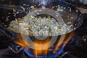 Wok Asian pan on a gas stove, on which is cooked rice with vegetables.