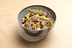 Wok with seafood and greens in a plate on a brown background