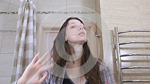 Woken tired woman in the bathroom smacks herself on the cheeks to Wake up.