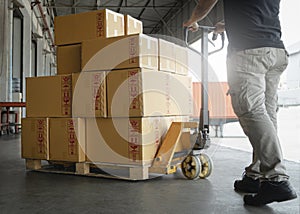 Woker working with hand pallet truck. worker unloading cardboard boxes stack on pallet rack. Shipment boxes. Cargo warehousing.