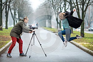 On the wolkway in town a guy takes a picture of a young girl