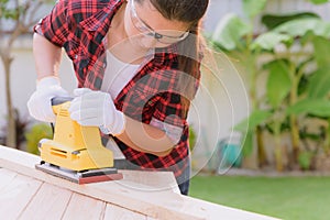 Womam Carpenter working with wood electrical sanding machine