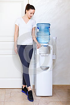 Woman, 20s, caucasian, standing at water cooler wearing sportwear