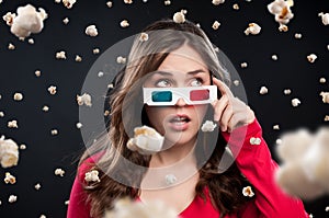 Woman, 3d glasses and shock with popcorn rain for snack, eating or watching movie in black studio background. Female