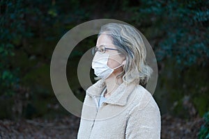 Woman 40-49 years outdoors, wearing glasses and white mask for protection against COVID-19 SARS-CoV-2 and other cont