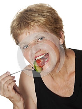 Woman (67 years old) eating vegetables from fork