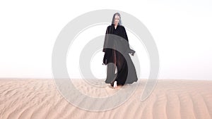 A woman in abaya walking in the desert. photo