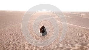 A woman in abaya walking in the desert.