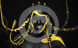 Woman on abstract poster with gold face art. Yellow and black colors of body paint. Young girl with bodypaint. An