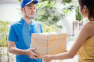 Woman accepting receive a delivery of boxes from delivery asian man photo