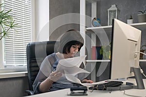 Woman accountant in office works with documents and contracts. Employee prepares quarterly report