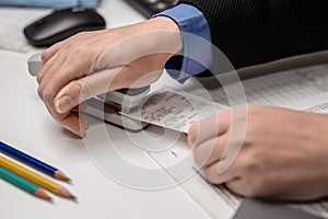 Woman accountant staples checks with a stapler at the office on the table