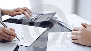 Woman accountant using a calculator and laptop computer while counting taxes for a client. Business audit concepts