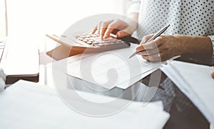 Woman accountant using a calculator and laptop computer while counting taxes for a client. Business audit and finance