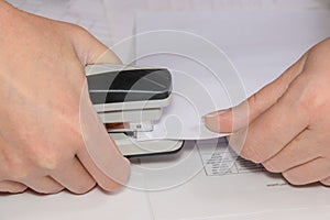 Woman accountant using stapler with documents on table, close-up