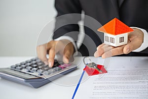 Woman accountant  worker uses calculator in the office to calculate house loan credit bureaucracy.Real estate investment concept