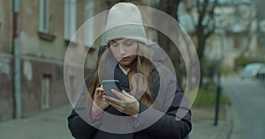 Woman activates smartphone digital virtual app voice assistant recording audio messages at outdoor. Young Girl in hat