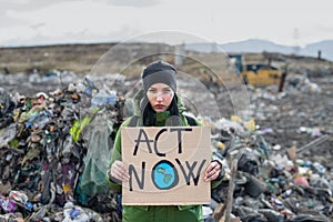 Woman activist with placard poster on landfill, environmental pollution concept.