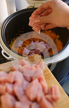 woman adding chicken fillet to slow cooker
