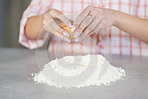 Woman adding an egg to a flour mound