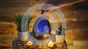 Woman adding essential oil to electric diffuser lamp, Aromatherapy