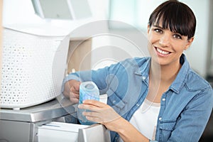 woman adding fabric softener to washing machine