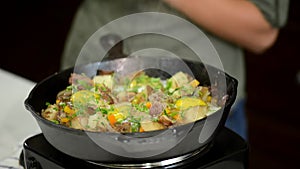 Woman adding green onion unto cast-iron frying pan.