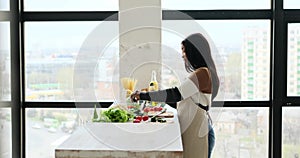 Woman adding olive oil and sprouts in mixing bowl