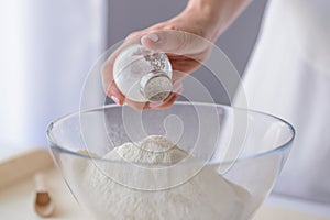 Woman adding salt to flour.