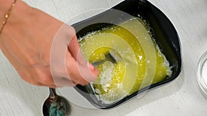 Woman adding salt to melted butter mixing in bowl cooking on kitchen at home.