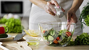 Woman adding salt in vegetable salad glass bowl, health care, excessive salting photo