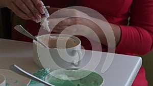 A woman adds a drop of food coloring from a tube of cream cheese. Coloring cream for lubrication of the cake.