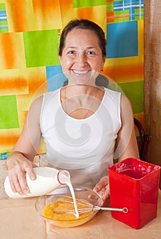 Woman adds milk into dish